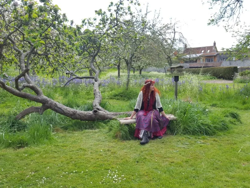 Raquel sentada entre los árboles de un jardín